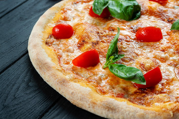 Homemade fresh Pizza Margherita with red sauce, basil and cherry tomato on a black wooden with copy space. Top view food photo. Flat lay. Italian cuisine.