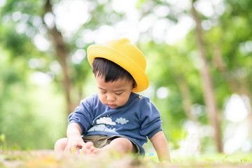Kid boy with yellow hat travel in green city park