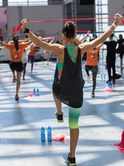 People Exercising with Fitness Elastic Band in Class at Gym with Music and Teacher on Stage.