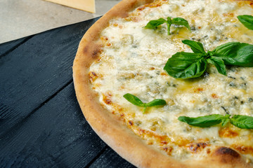 Homemade fresh Pizza with four cheese and basil on a black wooden with copy space. Top view food photo. Flat lay. Italian cuisine. Close up