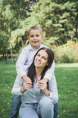 Fototapeta premium Eight year old son hugs mom in the park on the lawn