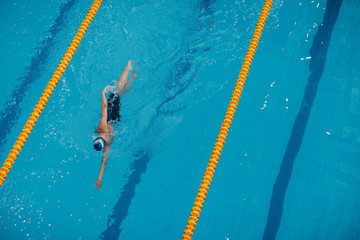 Young woman swimmer swims in swimming pool