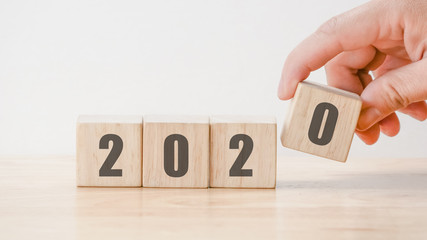 2020  New year countdown design concept , hand holding wood blocks cubes on wooden table  background