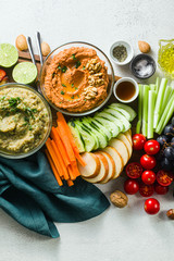 veggie serving table with snacks with vegetables, fruits, baba ganoush and dip or spread of roasted red pepper and nuts. healthy vegan food for celebration or friends. shot from above. copy space