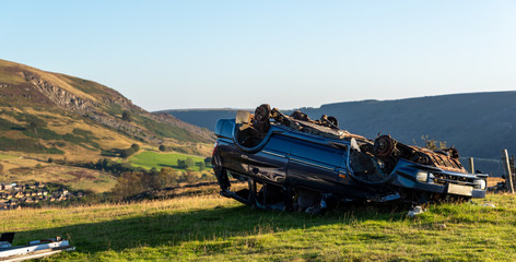 Unrecognisable abandoned car on its roof in the Welsh countryside, Wales, UK