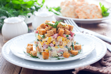 Salad with smoked sausage and crackers on a white plate in a portion serving, horizontal