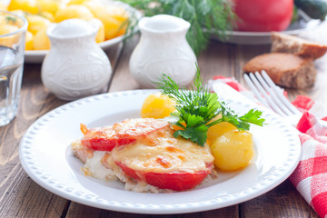 Baked pink salmon with tomato and cheese on a white plate with potatoes, horizontal