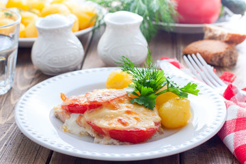 Fototapeta na wymiar Baked pink salmon with tomato and cheese on a white plate with potatoes, horizontal