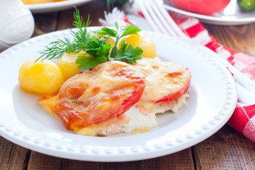 Baked pink salmon with tomato and cheese on a white plate with potatoes, horizontal