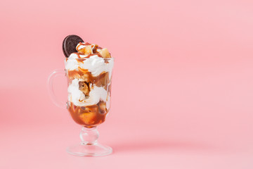 Sweet dessert in glass with biscuit and whipped cream on pink bsckground, selective focus and blank space