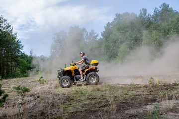Man riding a yellow quad ATV all terrain vehicle on a sandy forest. Extreme sport motion, adventure, tourist attraction. © volody10