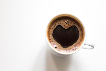 white mug with freshly brewed coffee, with a foam on the surface in the shape of a heart