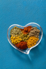 Oriental spices in a bowl in the shape of a heart. On a blue background. Shot from above. Copy space