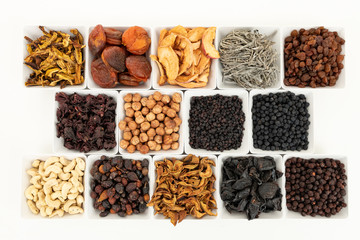 Groups of various kinds of dried fruits in square white bowls on white background