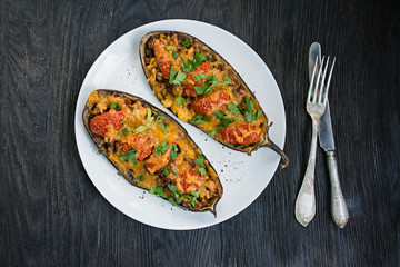 Stuffed Eggplant. Eggplant with minced meat, vegetables and herbs. Wood background.