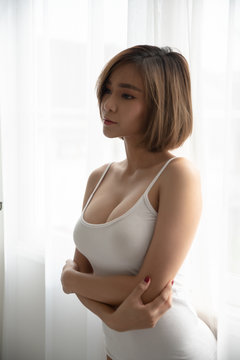 Attractive sexy asian woman standing near balcony window.