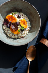 oatmeal in a bowl with bananas and blueberries on a table with blue napkin and bronze spoon
