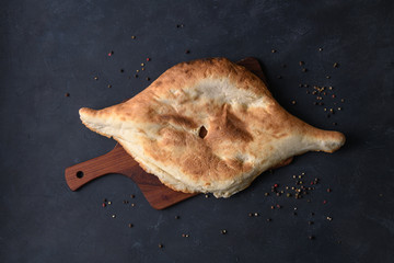 Georgian bread lavash on wooden board on dark rustic background, top view