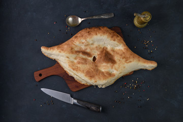 Georgian bread lavash on wooden board on dark rustic background, top view