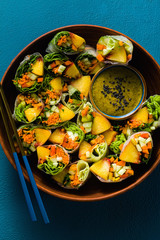 vegan spring rolls of vegetables and peach with pistachio sauce on a tray. healthy food . shot from above. copy space