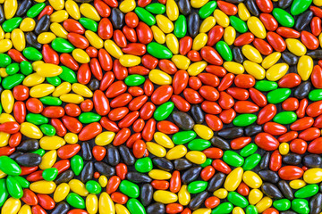 Background in the form of small sweets of milk chocolate covered with multi-colored glaze