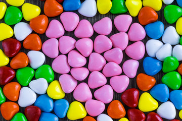 Background in the form of small sweets in the shape of a heart made of milk chocolate