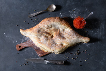 Georgian bread lavash with red caviar on wooden board on dark rustic background, top view