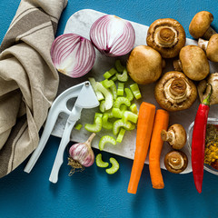 Ingredients for cooking Indian curry from vegetables, pumpkins and mushrooms on a blue background and spices. shot from above. copy space