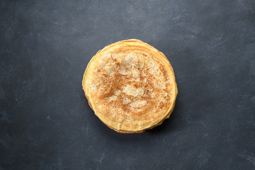 Stack of pancakes on dark rustic background, top view
