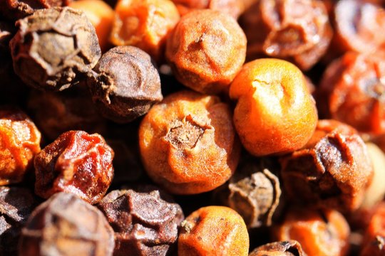 Macro close up of isolated pile with red and black kampot peppercorns from Cambodia