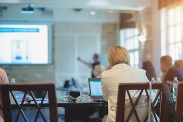Business woman in a white jacket sits at a table at a conference