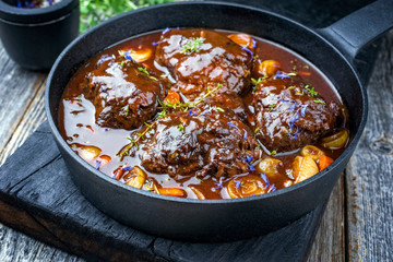 Traditionelle geschmorte Ochsenbacken mit Gemüse und Zwiebel in würziger brauner Sauce angeboten...