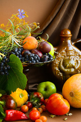  Still life of fruits and vegetables, flowers, wine in a clay jug with glasses on a brown background.  Happy Thanksgiving Day