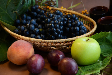 Autumn still life of fruits - blue grapes, plums, apples and peaches