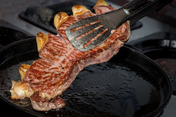 The cook is frying a steak