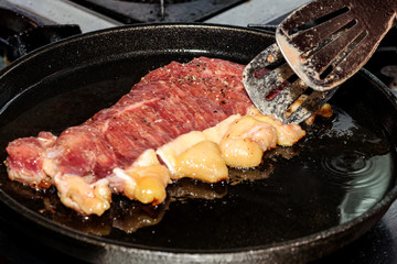 The cook is frying a steak