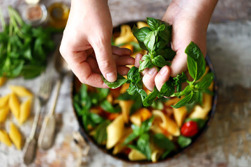 Hands of a chef with basil for cooking Italian pasta. Cooking one pan pasta.