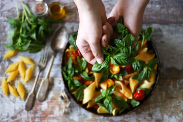 Hands of a chef with basil for cooking Italian pasta. Cooking one pan pasta.