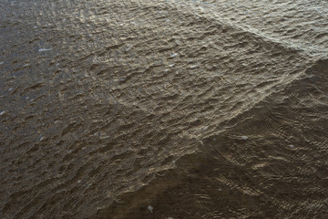 The surface of the water wind-blown in shallow water in the tidal zone with long stripes from the incident wave