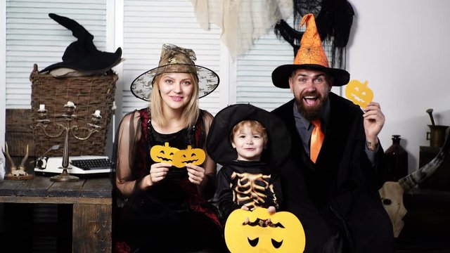 Happy family in halloween costumes with pumpkins. Happy family during halloween celebration. Faces covered with pumpkins for Halloween. Family halloween concept.