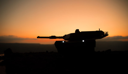 Fototapeta premium War Concept. Armored vehicle silhouette fighting scene on war fog sky background. American tank at sunset.