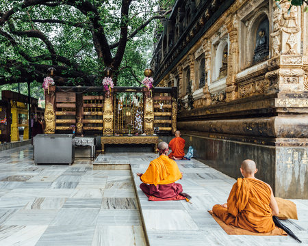 Indian Buddhist monk in meditation near The Bodhi Tree near Mahabodhi Temple while raining at Bodh Gaya, Bihar, India.