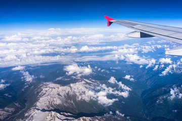 Fototapeta na wymiar Wing of an airplane flying above beautiful cloud