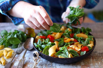 Hands of a chef with basil for cooking Italian pasta. Cooking one pan pasta.