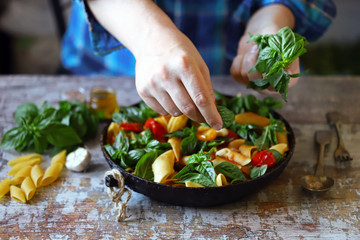 Hands of a chef with basil for cooking Italian pasta. Cooking one pan pasta.