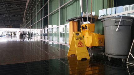 The warning signs cleaning and caution wet floor in the building and janitorial car.