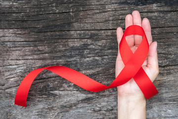 World aids day and national HIV/AIDS and ageing awareness month with red ribbon on woman hand...