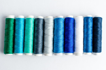 One line of colourful blue spools of thread displayed horizontally, isolated on white, top view