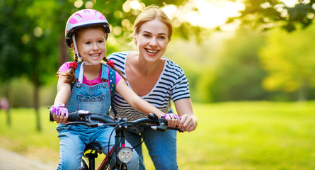 happy family mother teaches child daughter to ride a bike in the Park  .