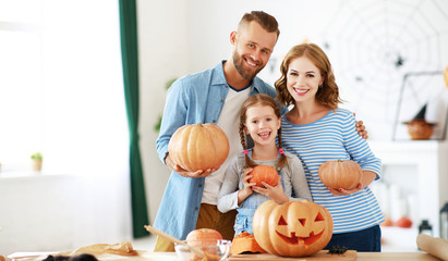 happy  family mother father and child daughter prepare for Halloween decorate  home with pumpkins,  laughing and  play  .